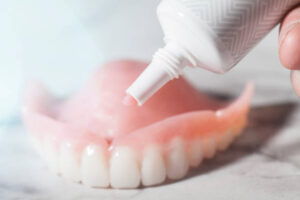 Paste adhesive being applied to upper denture